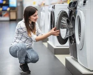 A young woman in a store chooses a washing machine.